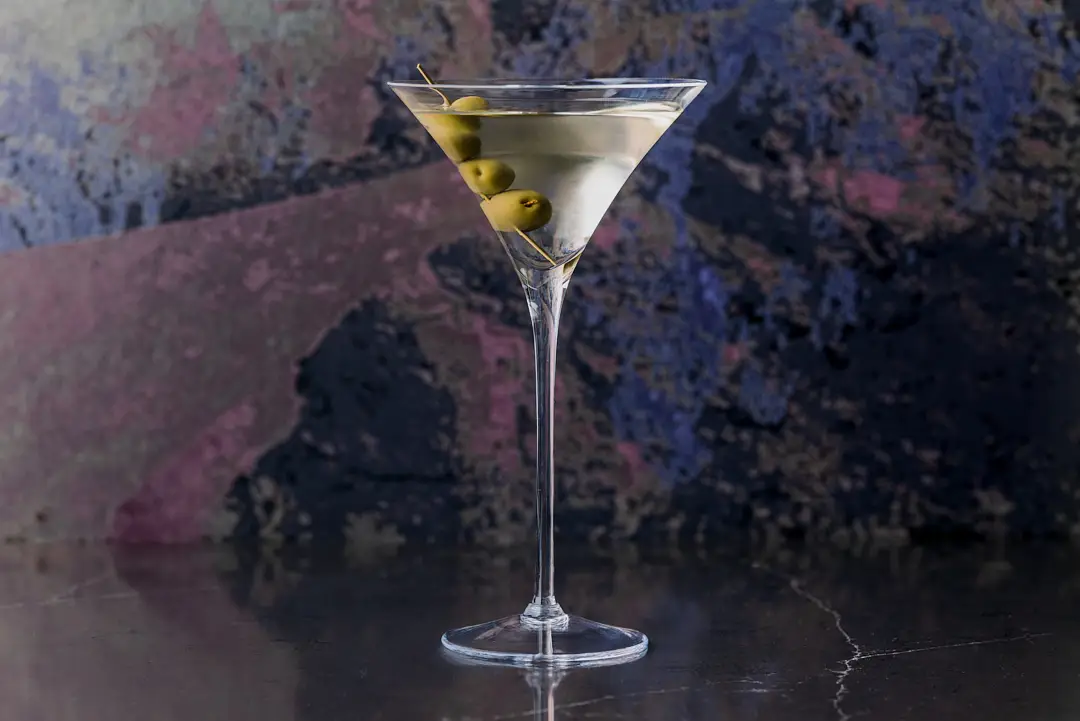 Martini cocktail served in a chilled glass with a lemon twist garnish, photographed against a textured stone background.