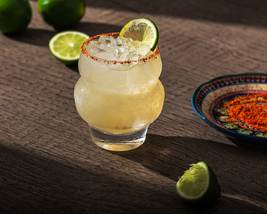 Margarita cocktail in a salt-rimmed glass with lime wedges
