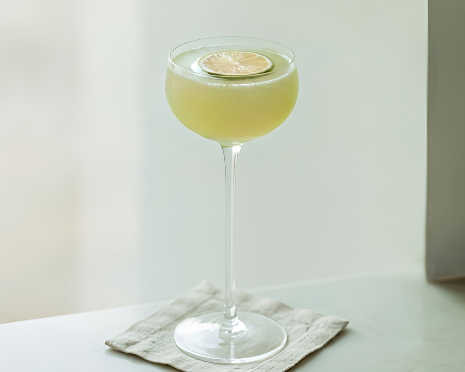 Classic daiquiri cocktail in a coupe glass with lime wheel garnish on a neutral background