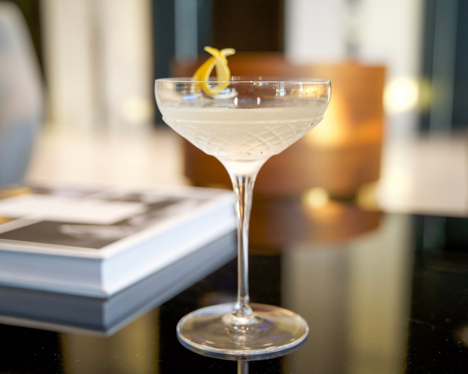 A Lemon Drop cocktail served up in a coupe glass, garnished with a lemon twist.