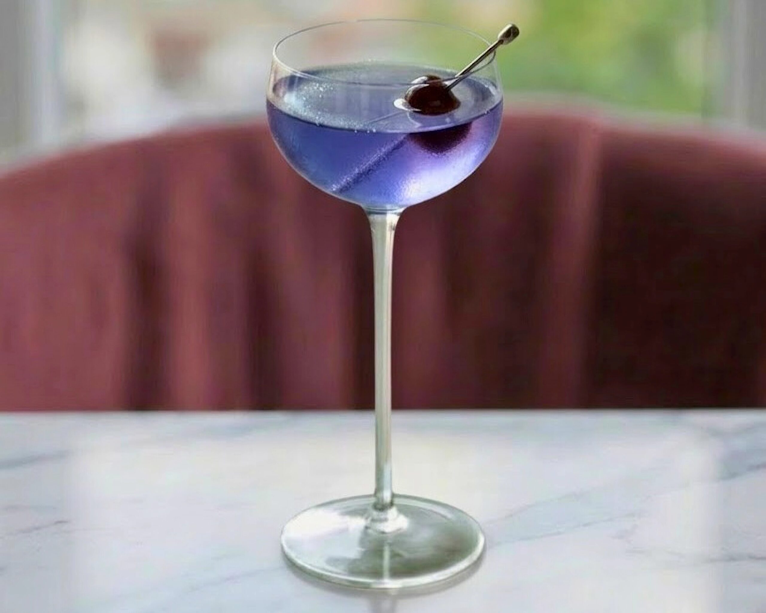 Aviation cocktail in a coupe glass with a dark cherry garnish