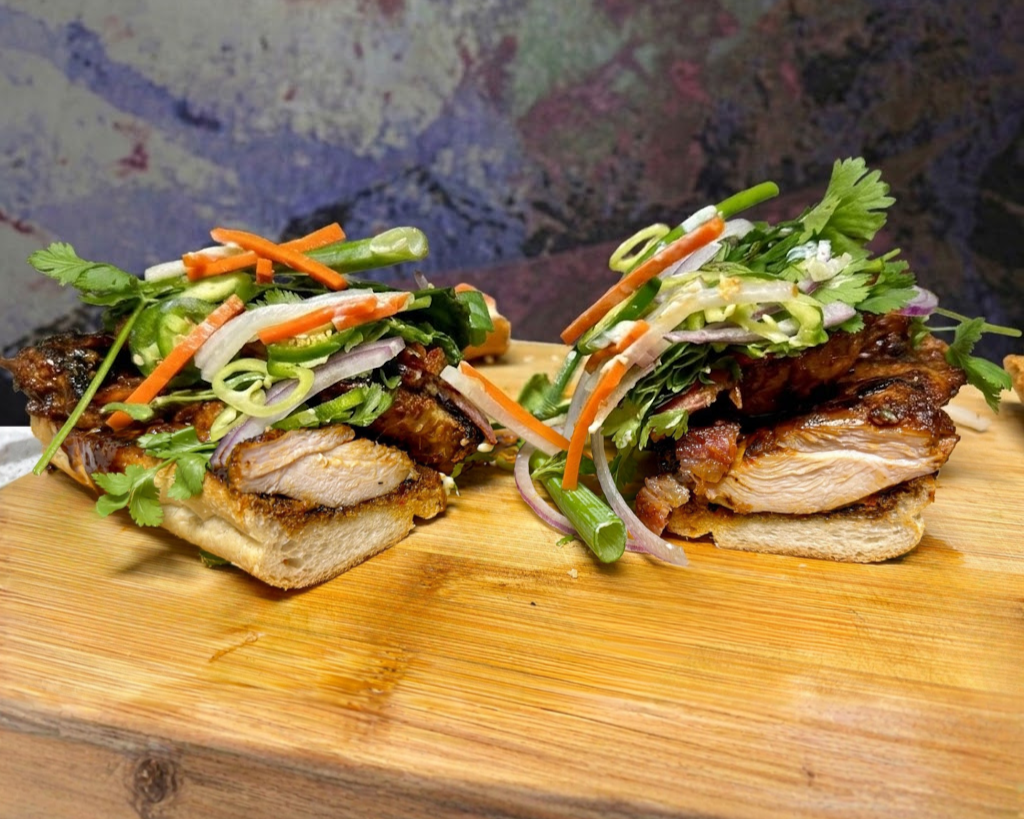 Vietnamese bánh mì sandwich with grilled chicken, pickled carrots, cucumber, and cilantro on a baguette.