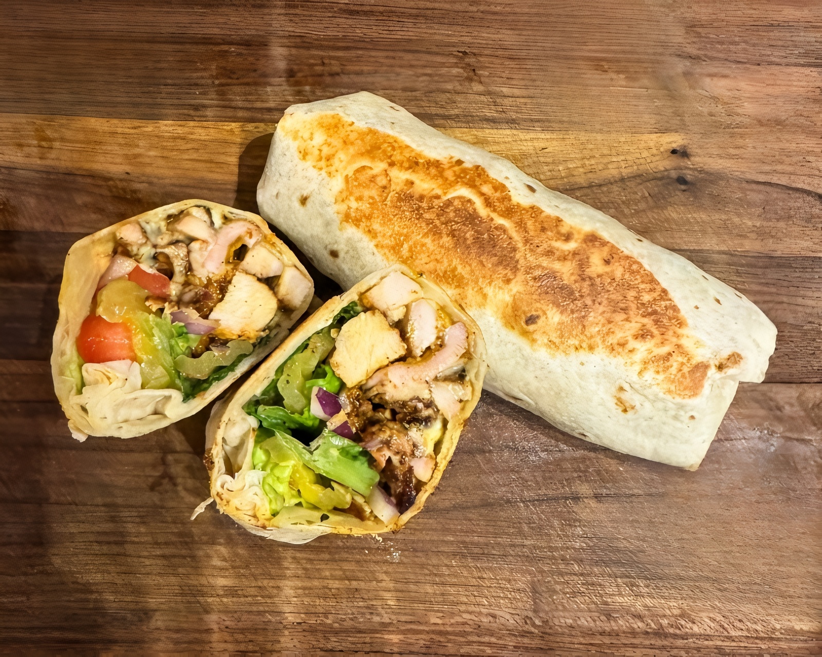 Chicken shawarma wrap sliced open on a wooden cutting board.