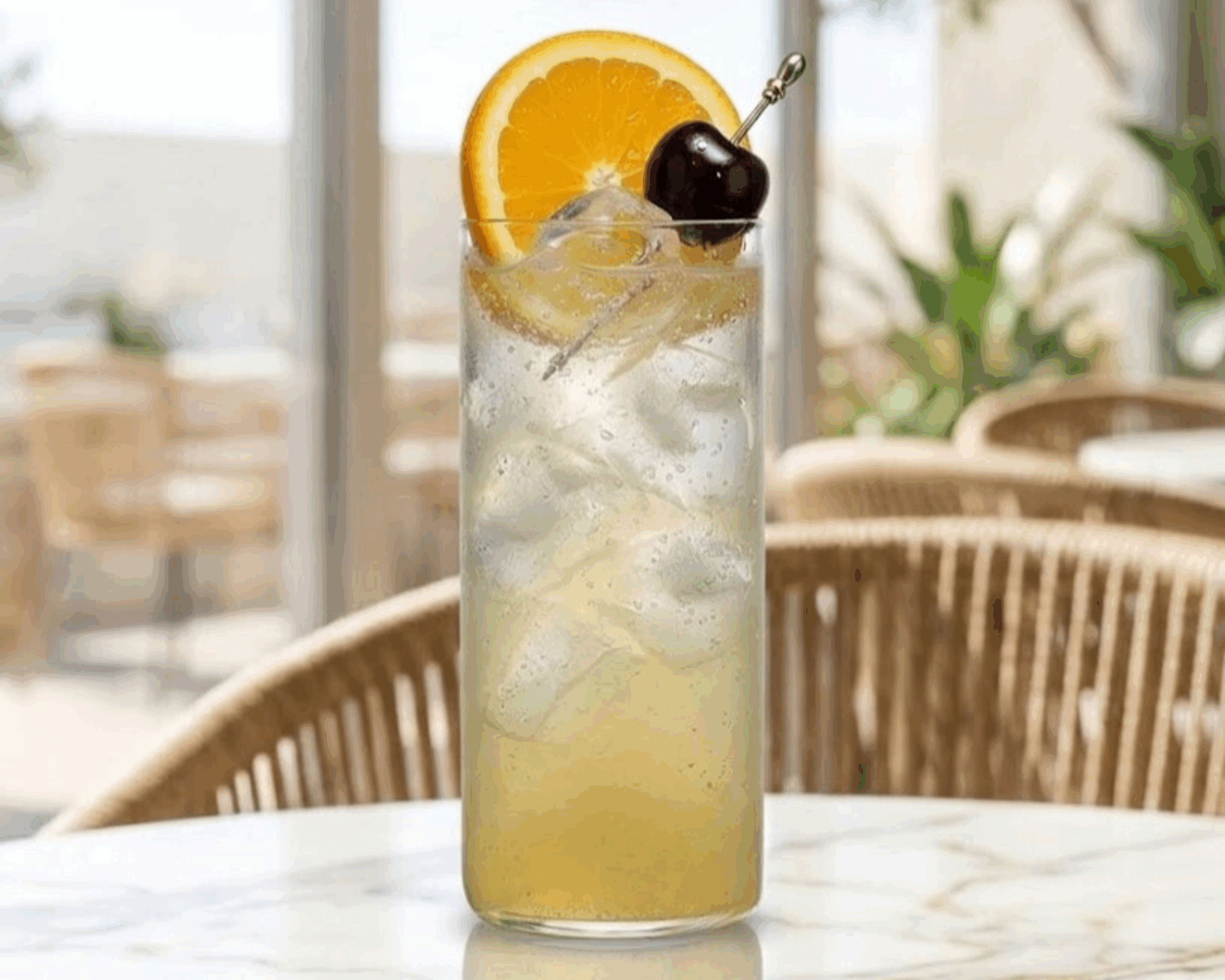 Tom Collins cocktail in a Collins glass with orange slice and cherry